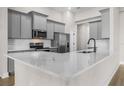 Modern kitchen features stainless steel appliances, stylish gray cabinets, and a stunning white quartz countertop at 12140 Warden Ave, Port Charlotte, FL 33981