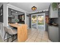 Bright kitchen with gray cabinets, a breakfast bar, and sliding glass doors leading to the deck and backyard at 1619 Coppertree Dr, Tarpon Springs, FL 34689