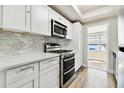 Modern kitchen with white cabinets, stainless steel appliances, and marble backsplash at 5875 21St N St # 15L, St Petersburg, FL 33714