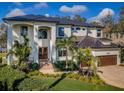 Beautiful two-story home featuring an arched entryway, lush landscaping, a two-car garage, and a dark metal roof at 1100 Monterey Ne Blvd, St Petersburg, FL 33704
