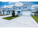 Two-story light blue townhome with white garage door and paver driveway at 2509 Mario Way, Clearwater, FL 33761