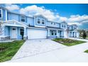 Two-story light blue townhome, white garage doors, paver driveway at 2509 Mario Way, Clearwater, FL 33761