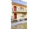 Two-story building with two units, red doors, and small yard at 11701 Raintree Village Blvd # C, Temple Terrace, FL 33617