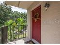 Inviting red front door entrance to condo, with a view of lush green trees at 11701 Raintree Village Blvd # C, Temple Terrace, FL 33617