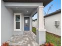 Covered front porch with blue door and a paved walkway at 9430 Shorebird Ct, Parrish, FL 34219