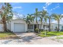 Charming single-story home with garage, brick driveway, tropical landscaping with green grass and palm trees at 422 86Th Ave, St Pete Beach, FL 33706