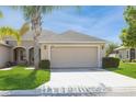 Tan one-story house with attached garage, palm tree, and well-manicured lawn at 13640 Eastfork Ln, Hudson, FL 34669