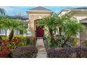 Elegant front entrance with stonework, lush landscaping, and a red door at 16623 Ashton Green Dr, Lutz, FL 33558