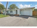 Ranch-style home with a white exterior, attached garage, and landscaped lawn at 3118 Adrian Ave, Largo, FL 33774