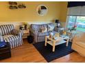 Living room features hardwood floors, striped sofas, and a coffee table at 2100 World Parkway Blvd # 14, Clearwater, FL 33763