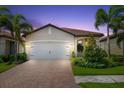 Single-story home with a tan exterior, white garage door, and landscaped front yard at dusk at 200 Soliera St, Nokomis, FL 34275