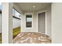 Covered front porch with gray door and brick flooring at 9446 Shorebird Ct, Parrish, FL 34219