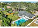 Aerial view of a home with a large pool, fenced yard, and mature trees in a lush, green neighborhood at 164 23Rd Sw Ave, Largo, FL 33778