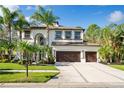 Two-story home featuring a three-car garage, a well-manicured lawn, and lush tropical landscaping at 3405 Loggerhead Way, Wesley Chapel, FL 33544