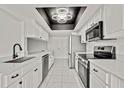 Modern kitchen featuring sleek white cabinets, stainless steel appliances, and contemporary lighting fixture at 7231 Big Bend Dr, Spring Hill, FL 34606