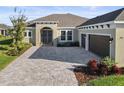 Tan house with a three-car garage and paver driveway at 3901 Tour Trce, Land O Lakes, FL 34638