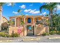 Building facade featuring arched entry, gated entrance, and palm trees at 2691 Woodette Dr # D, Dunedin, FL 34698