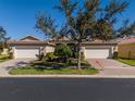 Home exterior featuring a brick driveway, two car garage, and beautifully maintained landscaping at 16233 Amethyst Key Dr, Wimauma, FL 33598