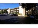 Condo building with parking lot and surrounding trees at 14130 Rosemary Ln # 2102, Largo, FL 33774