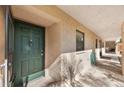 Exterior shot of front door with green finish, set in tan stucco with a decorative door knocker at 1753 Belleair Forest Dr # E2, Belleair, FL 33756