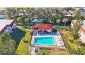 Aerial view of the community pool with lounge chairs and a shaded cabana, surrounded by lush landscaping at 1753 Belleair Forest Dr # E2, Belleair, FL 33756