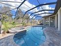 Beautiful screened-in pool and spa with brick pavers and lush landscaping at 11213 Warm Wind Way, Weeki Wachee, FL 34613