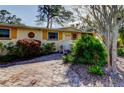 Bright yellow house with a brick driveway and tropical landscaping at 1747 Douglas Ave, Dunedin, FL 34698