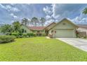 One-story house with light green walls, attached garage, and lush lawn at 9719 Pleasant Run Way, Tampa, FL 33647