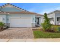 Light blue single-Gathering home with white garage door and brick paver driveway at 11275 Boundless Ter, Venice, FL 34293