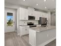 Modern kitchen with white cabinets, stainless steel appliances, and an island at 11275 Boundless Ter, Venice, FL 34293