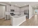 Modern kitchen with stainless steel appliances, white cabinetry, and a center island at 17909 Solstice Ave, Venice, FL 34293