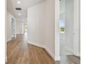 Bright hallway features wood-look floors, white walls, and doorways that lead to various rooms in the home at 11826 Richmond Trl, Parrish, FL 34219