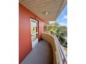 Corner view of the balcony with painted terracotta-colored walls, neutral railing, and partial tree views at 2021 Shangrila Dr # 60, Clearwater, FL 33763