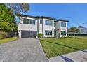Elegant home with a clean design, neat lawn, and paved driveway leading to a sleek black garage door at 4608 S Ferdinand Ave, Tampa, FL 33611