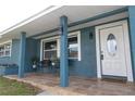 Quaint front porch with seating, stone tile, and a welcoming door at 1466 Laconia W Dr, Clearwater, FL 33764