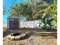 Backyard features a shed, fire pit, white fence, and lush tropical plants at 7521 Coventry Dr, Port Richey, FL 34668