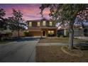 Two-story house with a brown exterior, driveway, and landscaping at dusk at 708 Fern Leaf Dr, Ruskin, FL 33570