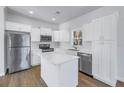Bright kitchen boasts white cabinetry, stainless steel appliances, and a center island with quartz countertop at 719 19Th S St, St Petersburg, FL 33712