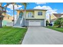 Two-story yellow house with gray steps, attached garage, and green lawn at 7145 Peninsular Dr, New Port Richey, FL 34652