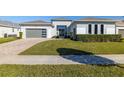 Modern home with gray siding, landscaping, and paver driveway at 9028 Ivy Stark Blvd, Wesley Chapel, FL 33545