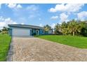 Newly built home with light blue exterior, paver driveway, and lush green lawn at 3471 Winona St, Port Charlotte, FL 33948