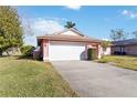 Pink house with a white garage door and a green lawn at 7853 Sundown Dr, St Petersburg, FL 33709