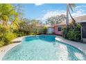 Inviting kidney-shaped pool with blue tile accents, surrounded by lush landscaping at 7853 Sundown Dr, St Petersburg, FL 33709
