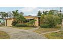 Inviting single-story home with a cozy covered front entry and lush greenery around the property at 2456 Tradewinds Dr, Dunedin, FL 34698