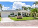 Single story home with white exterior, gray roof, and lush landscaping at 1615 Santa Barbara Dr, Dunedin, FL 34698