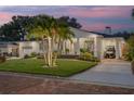 White house with palm trees, brick driveway and manicured lawn at 1615 Santa Barbara Dr, Dunedin, FL 34698