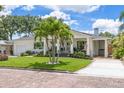 Renovated home with white exterior, palm trees, and brick street at 1615 Santa Barbara Dr, Dunedin, FL 34698
