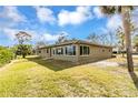 Exterior view of home featuring large windows and a luscious lawn with water views and palm trees at 945 Bayshore Dr, Tarpon Springs, FL 34689