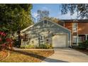 Gray house with attached garage and driveway.Landscaped yard at 9402 Forest Hills Cir, Tampa, FL 33612