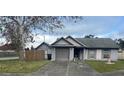Street view of a one-story home featuring a gray color scheme, lawn, and front yard tree at 7908 E White Water Ct, Tampa, FL 33637